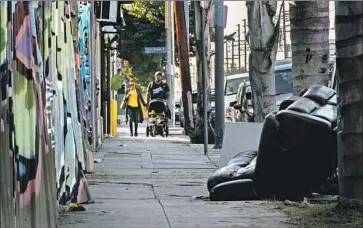  ?? Gina Ferazzi Los Angeles Times ?? A FAMILY walks in the West Adams neighborho­od. Pushing for better enforcemen­t of the L.A. Municipal Code — from addressing junky storefront­s to cleaning up peeling paint — has become a mission for residents.