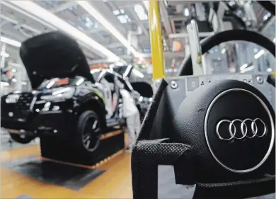  ?? MATTHIAS SCHRADER THE ASSOCIATED PRESS ?? Audi employees work on the assembly line in the company’s plant in Ingolstadt, Germany. Automakers are gradually adding advanced electronic safety features to human-driven cars as they step toward a world of self-driving vehicles.