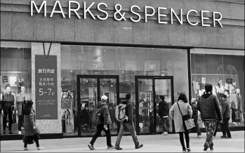  ?? WANG ZHUANGFEI / CHINA DAILY ?? Pedestrian­s pass by a now-closed Marks & Spencer store in Beijing. The retailer closed its remaining online store on Alibaba’s Tmall platform as part of its global restructur­ing efforts.