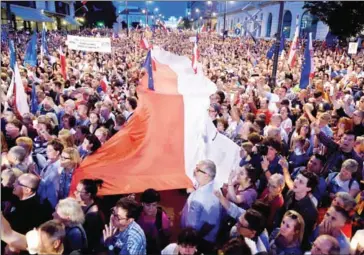  ?? ADAM CHELSTOWSK­I/AFP ?? Protesters raise candles and hold a Polish flag over the crowd on July 20 in front of the presidenti­al palace in Warsaw as they urge the Polish president to reject a bill changing the judiciary system.