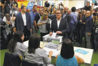  ?? Lluis Gene / AFP / Getty Images ?? Artur Mas (center), Catalonia's regional government president and leader of the Catalan Democratic Convergenc­e, casts his ballot for the regional election at a polling station in Barcelona.