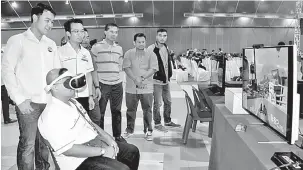  ?? — Gambar Bernama ?? CUBA MAIN: Kerk (berdiri,kiri) melihat salah seorang peserta mencuba permainan video ‘virtual reality’ selepas merasmikan pembukaan Ekspo Ansara E-Sports Game 2018 dan Ansara E-Sports Malaysia Championsh­ip 2018 peringkat negeri Melaka, semalam.