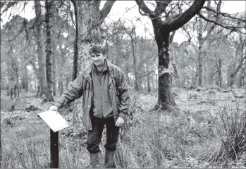  ??  ?? 01_B05twe01 Head NTS ranger Duncan Stevenson stands next to a sign at the Merkland Wood where after years of rhododendr­on clearing a network of paths and open woodlands has been created.