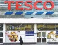  ?? REUTERSPIX ?? File photo shows a woman walks past a Tesco supermarke­t in central London.