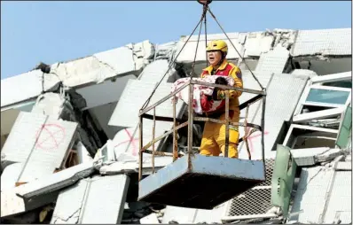  ?? AP/ WALLY SANTANA ?? An emergency worker cradles a 6- month- old girl rescued from the collapsed apartment building Sunday in Tainan, Taiwan.
