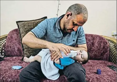  ?? MAHMUD HAMS / AFP ?? Mohamed al-Hadidi amb el seu fill Omar després de la mort en un bombardeig de la seva dona i quatre fills