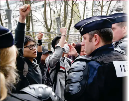  ??  ?? Demonstrat­ors from the Asian community face riot police officers outside Paris’ 19th district police station on Tuesday. Violent clashes in Paris between baton- wielding police and protesters outraged at the police killing of a Chinese man in his home...