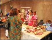  ?? LAUREN HALLIGAN - LHALLIGAN@TROYRECORD.COM ?? Event-goers shop for goods at booths representi­ng different countries during the 46th annual Festival of Nations, held Sunday at the Empire State Plaza Convention Center in Albany.