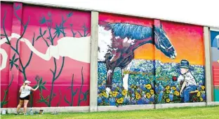  ?? College Station Eagle via AP ?? n Muralist Tyler Kay Reichert, top and above, paints her panel July 13 for a series of murals in downtown Bryan, Texas. She paints from sunrise until 11:30 a.m., then takes a break to avoid the sun until about 3:30 p.m., then paints until dark.