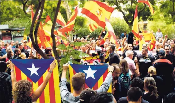  ?? AFP ?? Independen­tistas catalanes levantan su bandera durante una manifestac­ión, mientras ciudadanos contrarios a ese movimiento ondean la bandera de España durante una protesta en Barcelona, este viernes 22 de setiembre.