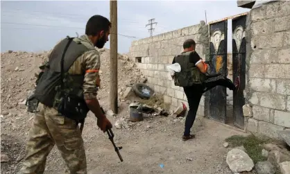  ??  ?? Turkey-backed Syrian fighters break open the front door of a house in Ras al-Ayn, a town now abandoned by Kurdish forces. Photograph: Nazeer Al-Khatib/AFP via Getty Images