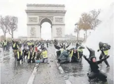  ??  ?? ► Los “chalecos amarillos” se enfrentan a la policía ayer, cerca del Arco de Triunfo, en París.