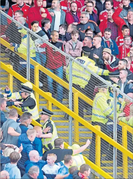  ??  ?? THIN BLUE LINE: Police attempt to quell unrest as rival fans hurl abuse, among other things, at each other at Pittodrie yesterday.