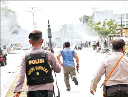  ?? SEVIANTO PAKIDING/AFP ?? Indonesian policemen disperse protesters in Timika, Indonesia’s restive Papua province, on Wednesday.