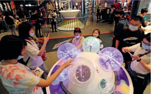  ??  ?? Visitors interact with a scientific device at the Shanghai Science and Technology Museum on May 23