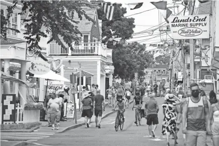  ?? MERRILY CASSIDY/USA TODAY NETWORK ?? Visitors walk along Commercial Street in Provinceto­wn wearing face masks this past summer. Many expect that face masks and other COVID-19 protocols will remain in effect this coming tourist season.