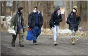  ??  ?? Jose Ortiz, left, a resident of the homeless encampment known as the Jungle, walks with Matt Dankanich, a community health worker for REACH Medical; Tas’a Towsley, a friend of Ortiz; and Deb Wilke, right, the homeless crisis alleviatio­n coordinato­r for Second Wind Cottages on Dec. 7 in Ithaca, N.Y.