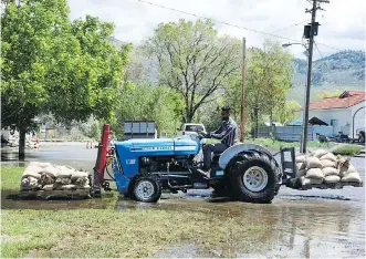  ?? NICK EAGLAND ?? Sandeep Jhinger uses a tractor to haul sandbags to help protect a friend’s house from flooding on Harbour Key Drive in Osoyoos.