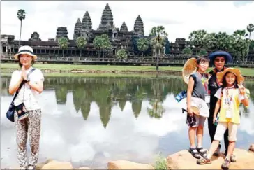  ?? HONG MENEA ?? Tourists have their photo taken in front of Angkor Wat in Siem Reap in 2014.