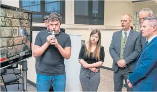  ??  ?? Adam Finch and Connie Reid of student games team Konglomera­te Games showcase their game for cystic fibrosis sufferers to Prof Gregor White, principal Nigel Seaton and Mr Mackay.