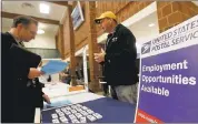  ?? KEITH SRAKOCIC — ASSOCIATED PRESS ?? A recruiter from the postal service, right, speaks with an attendee of a job fair in Cheswick, Pa. The number of unemployed continues to fall, but wages have remained flat.