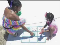  ?? ?? Charmaine Gray and her daughter, Niamya, 5, of San Bernardino play a game of tic tac toe at Saturday’s festival.