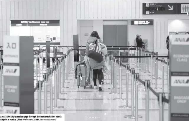  ?? AKIO KON/BLOOMBERG ?? A PASSENGER pushes luggage through a departures hall of Narita Airport in Narita, Chiba Prefecture, Japan.