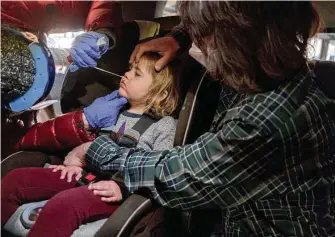  ?? September Dawn Bottoms / New York Times ?? Jason Abercrombi­e holds his daughter Mary during a COVID-19 test on Thursday in Broken Arrow, Okla. Mary, 2, was exposed to someone with the virus.