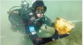  ??  ?? A diver holds one of the thousands of artifacts found in the depths of Lake Titicaca.