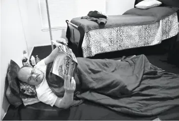  ?? Lea Suzuki / The Chronicle ?? LUIS CASTELLANO­S: The first person to leave supportive housing for his own apartment under the Moving On Initiative isn’t used to his own bed, so he lies on old blankets from camping in the park and reads to get to sleep.