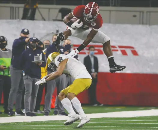  ?? MICHAEL AINSWORTH/THE ASSOCIATED PRESS ?? Alabama running back Najee Harris hurdles Notre Dame cornerback Nick Mccloud in the first half of the Rose Bowl NCAA college football game in Arlington, Texas, on Friday.