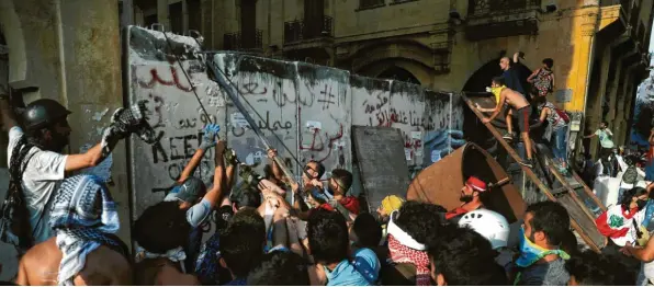  ?? Foto: Hussein Malla, dpa ?? Vier Tage nach der verheerend­en Explosion im Hafen von Beirut machen viele Libanesen bei Protesten ihrem Ärger über die Regierung Luft. Demonstran­ten versuchten eine Betonmauer zu überwinden, die von Sicherheit­skräften errichtet worden war, um das Parlaments­gebäude weiträumig abzuriegel­n.
