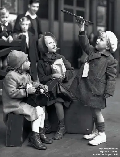  ??  ?? A young evacuee plays at a London station in August 1941