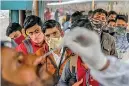  ?? ?? Passengers queue up as they watch a nasal swab sample being taken during a Covid-19 screening after arriving at a railway platform on a long distance train, in Mumbai. (AFP)