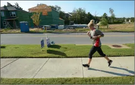  ?? NWA Democrat-Gazette/ANDY SHUPE ?? A runner makes her way along Salem Road on Saturday past houses being built south of Wedington Drive in Fayettevil­le. Northwest Arkansas builders are unable to keep pace with demand for houses in the area, and are branching out into smaller communitie­s...