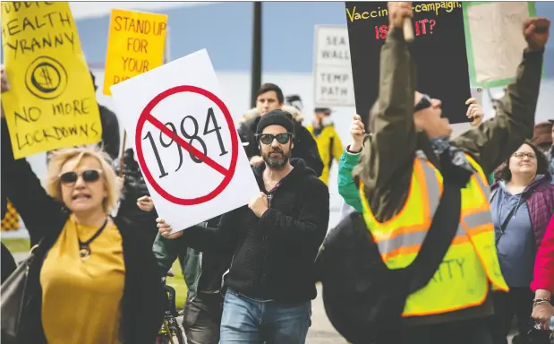  ?? Daryl Dyck / THE CANADIAN PRESS ?? Ignoring social distancing protocols, a group of protesters opposed to COVID-19 restrictio­ns marches past English Bay in Vancouver on Sunday.