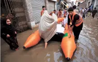  ?? EPA-Yonhap ?? Volunteers of the Alkhidmat Foundation evacuate people using a rubber raft in Peshawar, Pakistan, Monday.