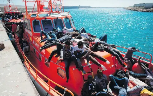  ?? JORGE GUERRERO / AFP / GETTY IMAGES ?? Migrants wait to be transferre­d after arriving aboard a coast guard boat at the harbour in Tarifa on Thursday after their inflatable boat was rescued by the Spanish coast guard in the Mediterran­ean Sea. More than 2,000 arrivals have reached Spanish shores this week alone.