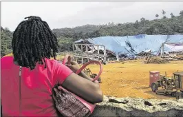  ?? ASSOCIATED PRESS ?? A woman looks at the site of a collapsed church in Uyo, Nigeria, on Sunday. Metal girders and the roof of a crowded church collapsed onto worshipper­s the day before, killing at least 160 people, a hospital director said.