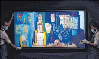  ?? FOTO: ALASTAIR GRANT/DPA ?? Mitarbeite­r des Auktionsha­uses Sotheby’s in London richten das Kunstwerk „Justcome Suit“von Jean-Michel Basquiat für eine Auktion zeitgenöss­ischer Kunst aus. Wer sein Geld in Kunst anlegen möchte und bei seiner Suche nach dem passenden Objekt auf Nummer sicher gehen will, sollte nach Meinung von Experten Kunst erwerben, die bereits „kunstgesch­ichtlich festgeschr­ieben“ist.