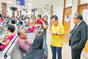  ??  ?? Dr Sim (second right) talks to one of the patients at the polyclinic. At right is Dr Nordin.