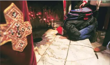  ?? AP ?? A worshipper kisses the ground near the silver star which marks the place where Jesus Christ is believed to have been born, in the Grotto at the Church of the Nativity, in the West Bank city of Bethlehem, on Saturday.