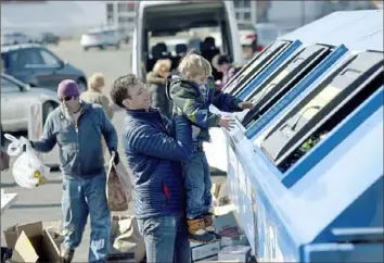  ?? Pam Panchak/Post-Gazette ?? Aaron Todd, of Upper St. Clair, lifts his son, Maxwell, 5, up to deposit glass into the Pennsylvan­ia Resources Council recycling dumpsters at the PRC's glass recycling pop-up collection event March 2019 in the Kohl's parking lot in Village Square Mall in Bethel Park. PRC Co-Executive Director Justin Stockdale is estimating 24,000 pounds (i.e. 12 tons) of glass was collected that day.