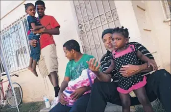  ?? Photog raphs by Michael Robinson Chavez Los Angeles Times ?? CRAIG McGRUDER spends some time at his Jordan Downs home in Watts with family members including his twin 17-year-old sons Victor, left, and Vincent, who is holding his own infant son, Vincent Jr.