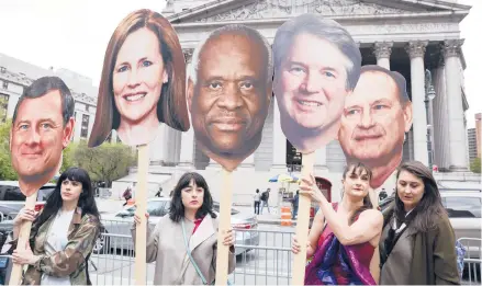  ?? CAITLIN OCHS/THE NEW YORK TIMES ?? Activists hold cutouts of Justices John Roberts, Amy Coney Barrett, Clarence Thomas, Brett Kavanaugh and Samuel Alito.