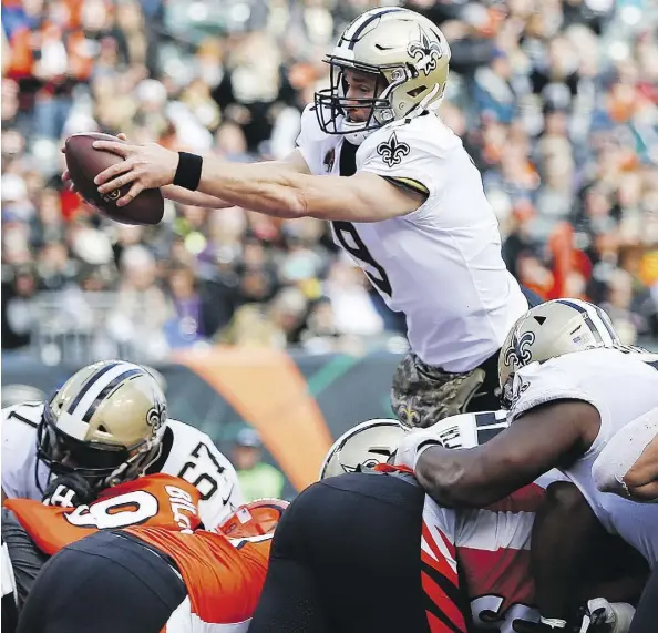  ?? FRANK VICTORES/THE ASSOCIATED PRESS ?? New Orleans Saints quarterbac­k Drew Brees goes airborne to score a touchdown in his team’s 51-14 victory over the Bengals Sunday in Cincinnati. The Saints won their eighth straight game and Brees passed Brett Favre for second in career touchdown passes.