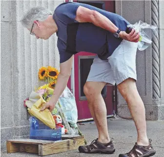  ?? STAFF PHOTO BY PATRICK WHITTEMORE ?? TRAGEDY: Mattapan resident Peter Byerly places flowers near the entrance to the Curley Community Center in South Boston yesterday in honor of Kyzr Willis, 7.