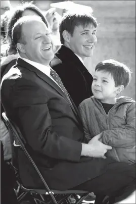  ?? AARON ONTIVEROZ / THE DENVER POST VIA AP ?? New Colorado Gov. Jared Polis, left, laughs with his partner, Marlon Reis, center, and their son Caspian during Polis’ inaugurati­on Jan. 8 in Denver.