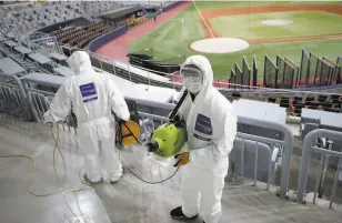  ?? Lee Jin-man / Associated Press ?? Workers wearing protective gear disinfect against COVID19 in Seoul, South Korea, before a baseball game. Such procedures may be more a matter of optics than science.