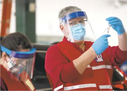  ?? HANNAH RUHOFF/STAFF ?? Volunteer medical workers prepare vaccines for patients during a drive-in vaccinatio­n event for health care workers at Oceana Volunteer Fire Department Station 8 in Virginia Beach on Tuesday.